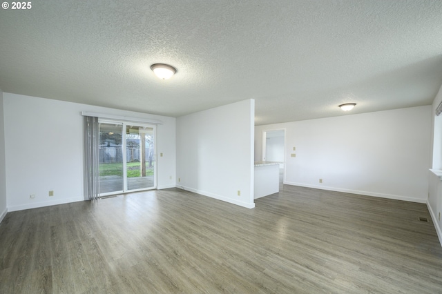 spare room featuring a textured ceiling, baseboards, and wood finished floors