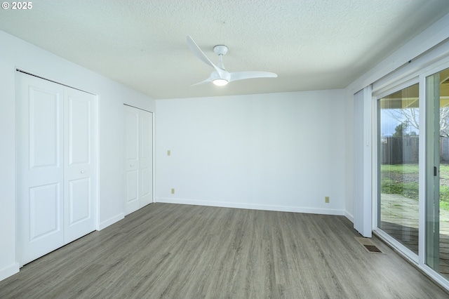 unfurnished bedroom with access to exterior, visible vents, a textured ceiling, and wood finished floors