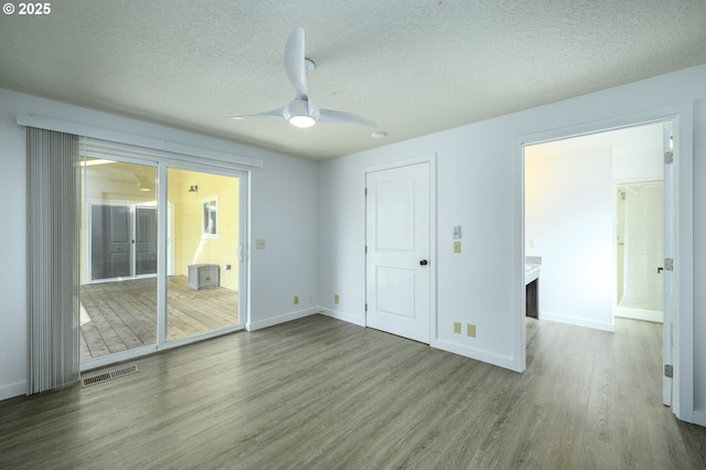 unfurnished bedroom featuring a textured ceiling, wood finished floors, a ceiling fan, visible vents, and baseboards