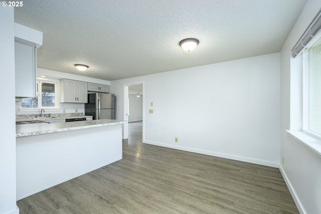 kitchen featuring dark wood-style floors, gray cabinets, freestanding refrigerator, and baseboards