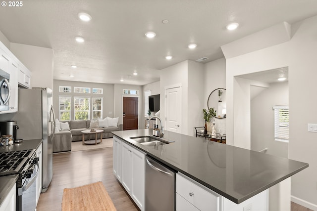 11469 SW Mont Blanc St, Wilsonville, OR 97070 - kitchen featuring appliances with stainless steel finishes, dark countertops, recessed lighting, open floor plan, and light wood-type flooring