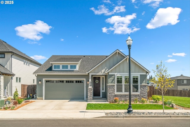 craftsman-style home featuring a front lawn, board and batten siding, roof with shingles, concrete driveway, and fence