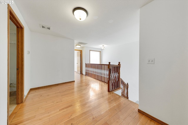 hallway with an upstairs landing and light wood-type flooring