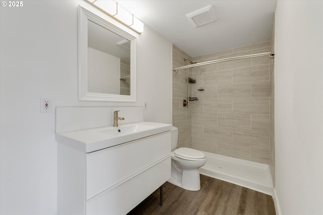 full bath featuring vanity, wood finished floors, and a tile shower