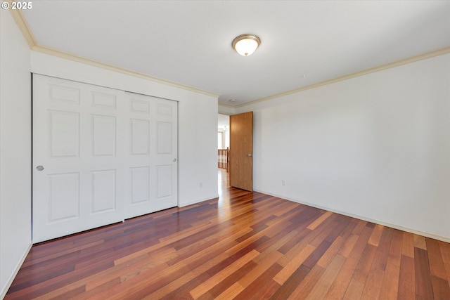 unfurnished bedroom with crown molding, wood finished floors, and a closet