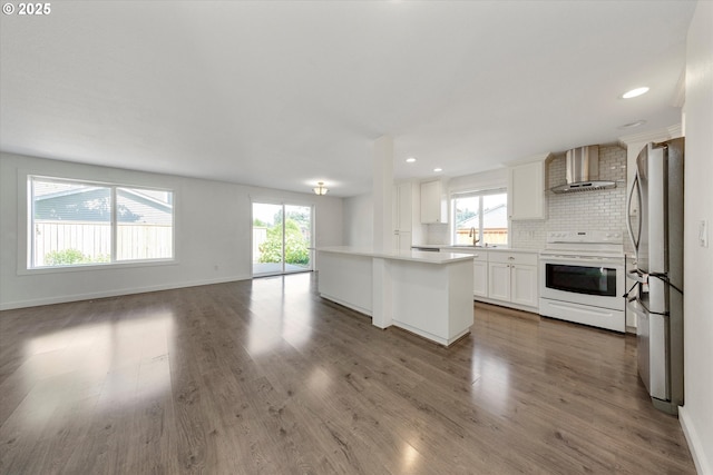 kitchen with white electric range oven, wall chimney exhaust hood, freestanding refrigerator, open floor plan, and backsplash