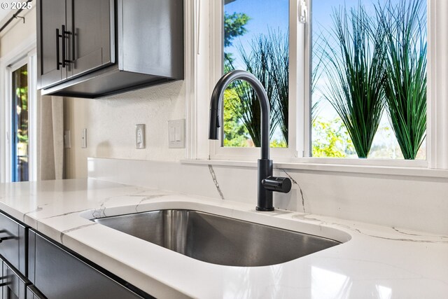interior details with gray cabinetry, light stone countertops, and a sink