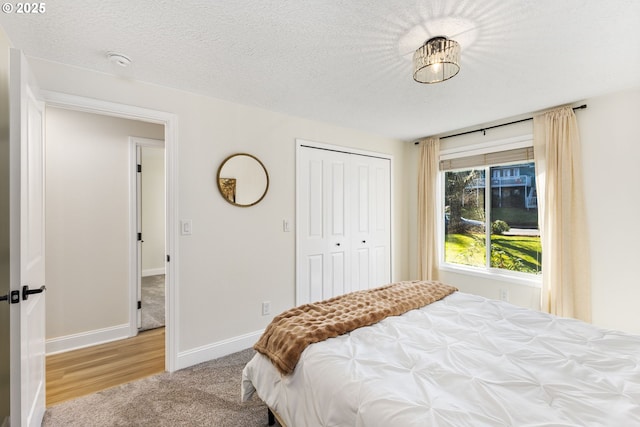 carpeted bedroom featuring a closet, a textured ceiling, and baseboards
