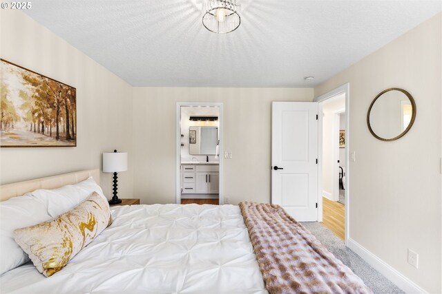 bedroom featuring baseboards, connected bathroom, carpet, and a sink