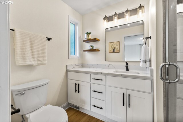 bathroom featuring vanity, toilet, an enclosed shower, baseboards, and wood finished floors