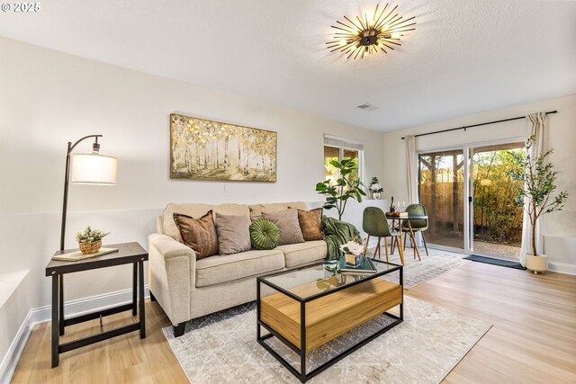 living area with baseboards, visible vents, and light wood-style flooring