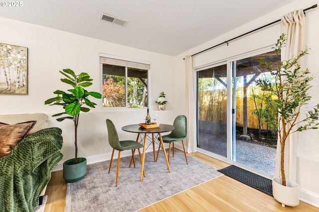 dining space with visible vents, wood finished floors, and baseboards