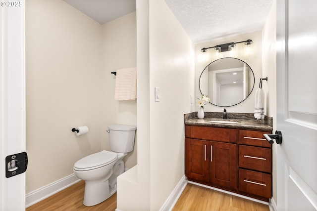 half bathroom featuring toilet, wood finished floors, and baseboards