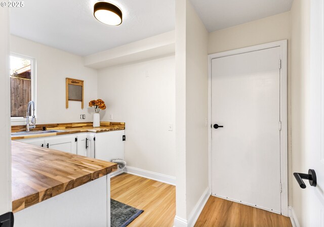 interior space featuring light wood-style floors, baseboards, and a sink