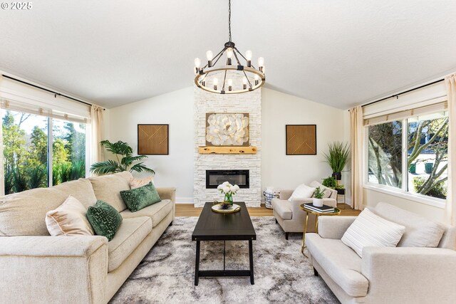 living room with a wealth of natural light, light wood-style floors, a notable chandelier, and vaulted ceiling