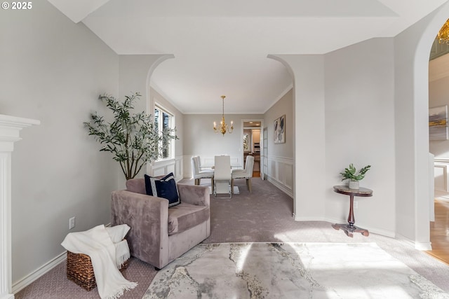 living room with ornamental molding, a chandelier, and carpet flooring