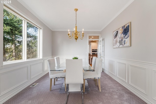 carpeted dining space featuring ornamental molding and a chandelier