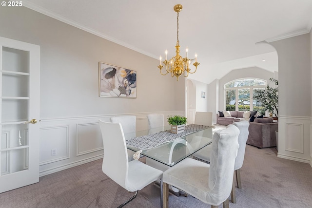 carpeted dining room with crown molding, an inviting chandelier, vaulted ceiling, and built in features