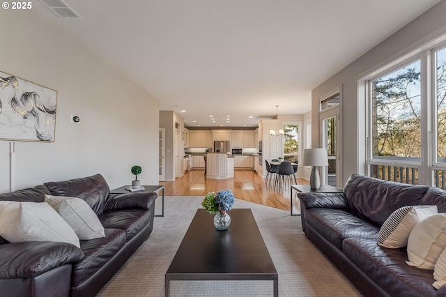 living room with a notable chandelier and light hardwood / wood-style floors