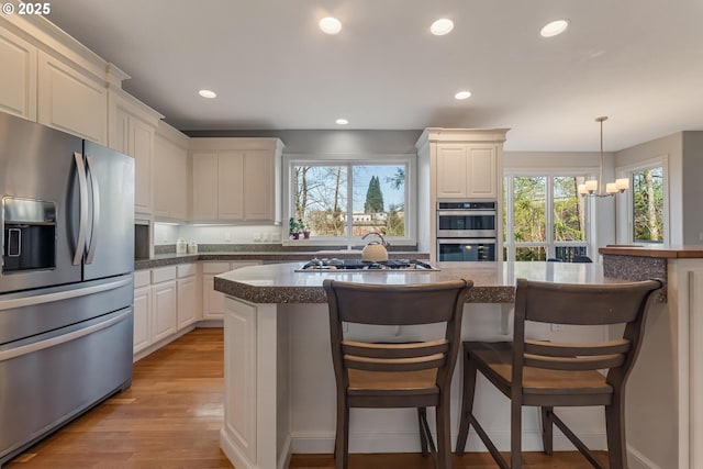 kitchen featuring white cabinetry, appliances with stainless steel finishes, a wealth of natural light, and decorative light fixtures