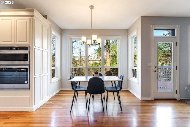 dining space featuring a healthy amount of sunlight, a chandelier, and light hardwood / wood-style flooring