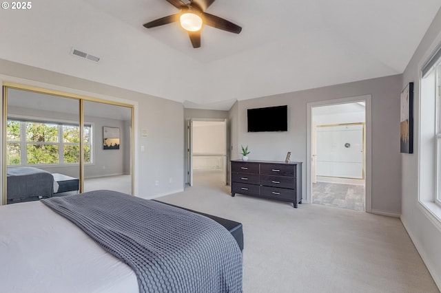 carpeted bedroom featuring a raised ceiling, connected bathroom, a closet, and ceiling fan