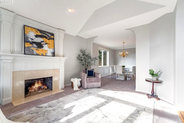 sitting room featuring vaulted ceiling, a fireplace, ornamental molding, light colored carpet, and an inviting chandelier