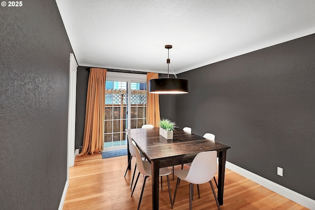 dining area featuring a textured ceiling and light hardwood / wood-style flooring