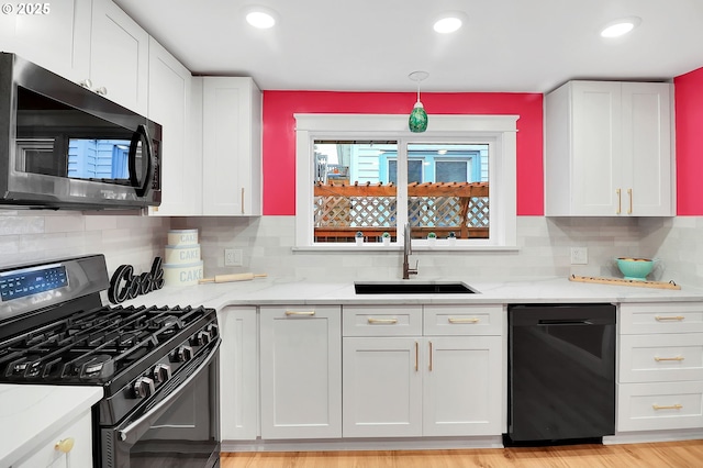 kitchen with tasteful backsplash, light stone countertops, black appliances, white cabinets, and sink