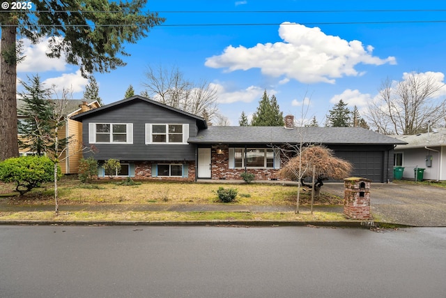 split level home with a garage, driveway, brick siding, and a front lawn