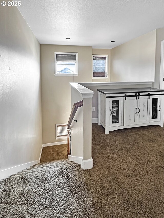 staircase with visible vents, carpet flooring, a textured ceiling, and baseboards