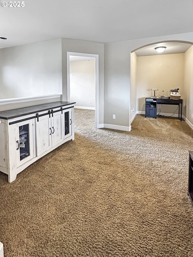 interior space featuring baseboards, arched walkways, and carpet