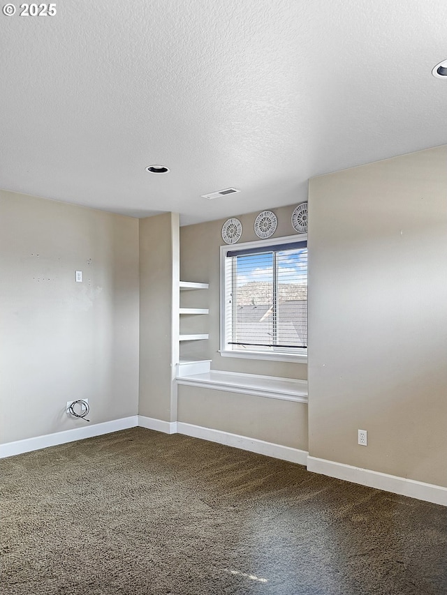 empty room featuring carpet, baseboards, visible vents, and a textured ceiling