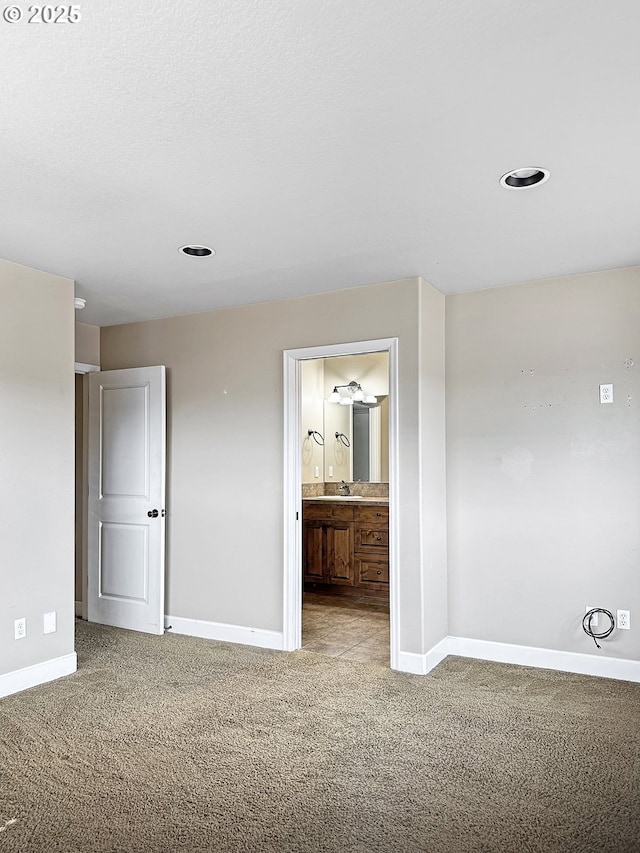 unfurnished bedroom featuring a sink, baseboards, carpet floors, and connected bathroom