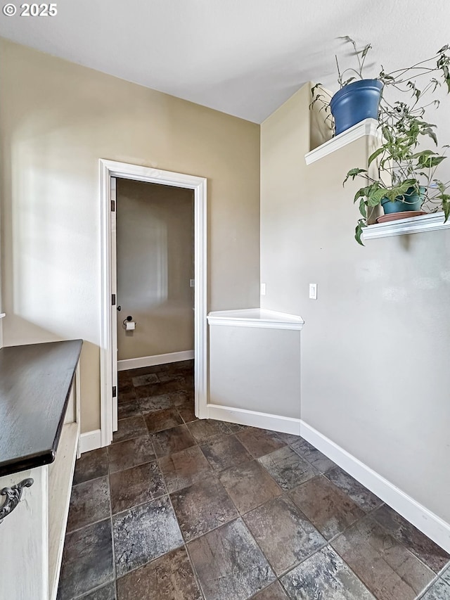 laundry room with stone tile flooring and baseboards