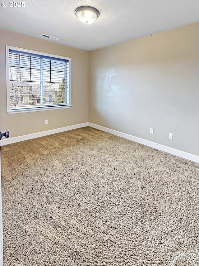 carpeted spare room featuring visible vents, baseboards, and a textured ceiling