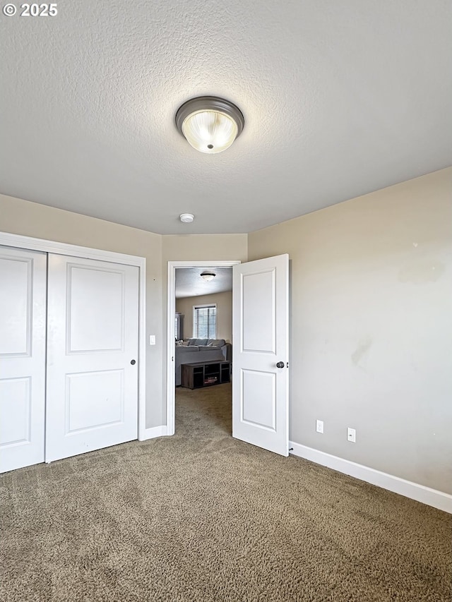 unfurnished bedroom with a closet, baseboards, a textured ceiling, and carpet flooring