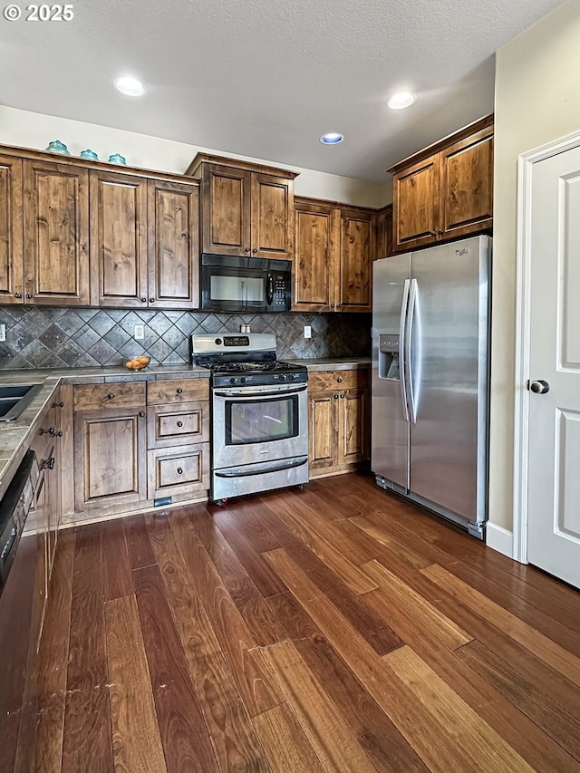 kitchen featuring dark wood-type flooring, backsplash, a textured ceiling, recessed lighting, and stainless steel appliances