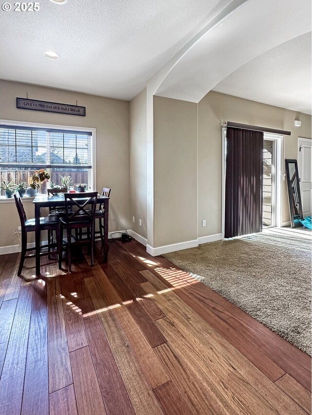 dining space featuring a textured ceiling, baseboards, and hardwood / wood-style floors