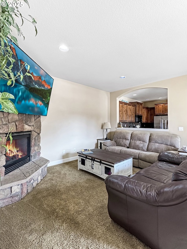 carpeted living room featuring recessed lighting, a fireplace, a textured ceiling, and baseboards