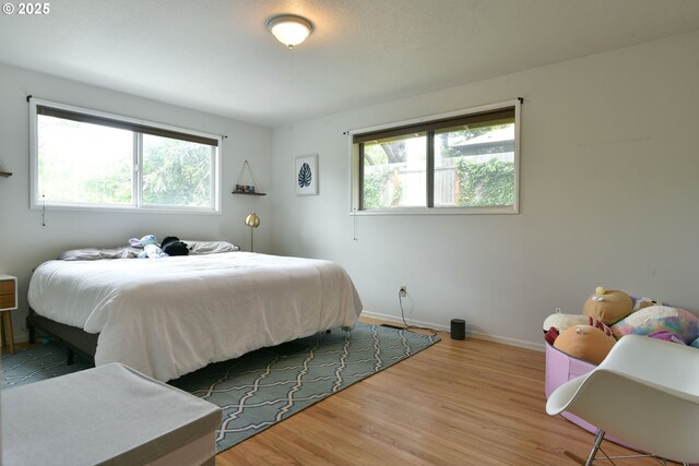 8302 SW 65th Ave, Portland, OR 97219 - bedroom with wood finished floors, multiple windows, and baseboards