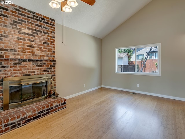 5367 NW 180th Pl, Portland, OR 97229 - unfurnished living room featuring wood finished floors, high vaulted ceiling, a fireplace, ceiling fan, and a textured ceiling