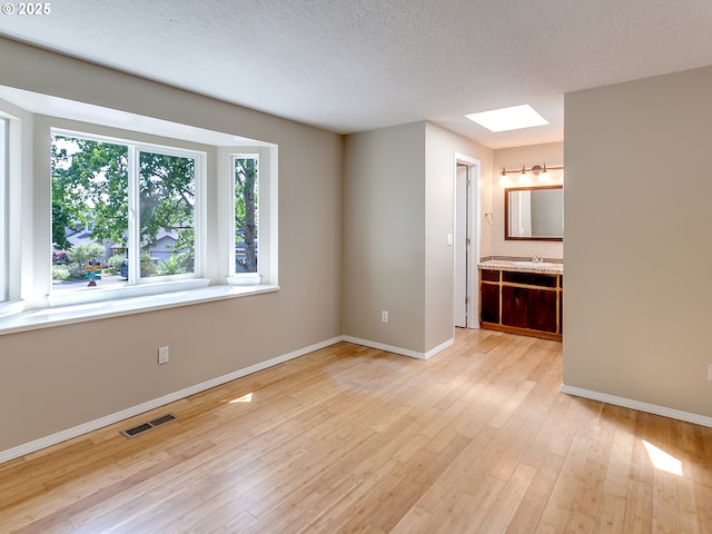 5367 NW 180th Pl, Portland, OR 97229 - spare room featuring a skylight, wood-type flooring, and a textured ceiling