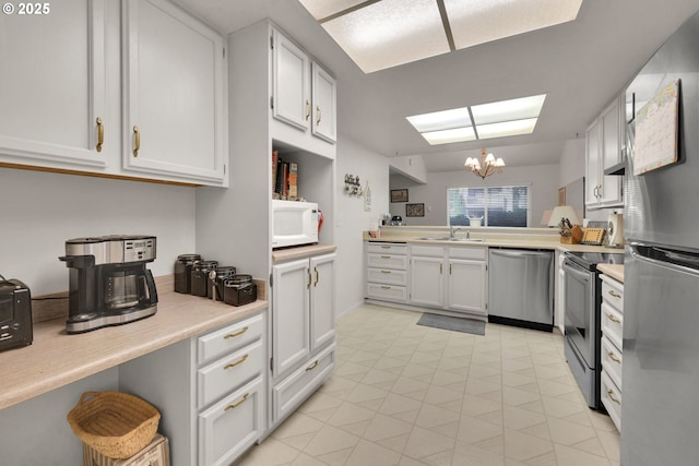 2062 Lake Isle Dr, Eugene, OR 97401 - kitchen featuring appliances with stainless steel finishes, a chandelier, light countertops, and white cabinetry