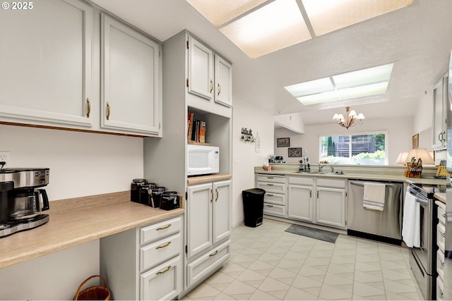 2062 Lake Isle Dr, Eugene, OR 97401 - kitchen featuring appliances with stainless steel finishes, a chandelier, light countertops, and light tile patterned floors
