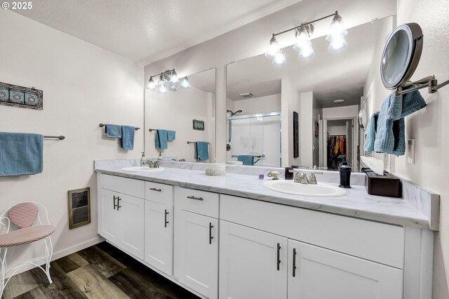2062 Lake Isle Dr, Eugene, OR 97401 - full bathroom with a stall shower, double vanity, wood finished floors, a walk in closet, and heating unit