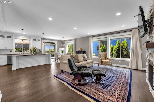 living area with recessed lighting, a stone fireplace, dark wood finished floors, and baseboards