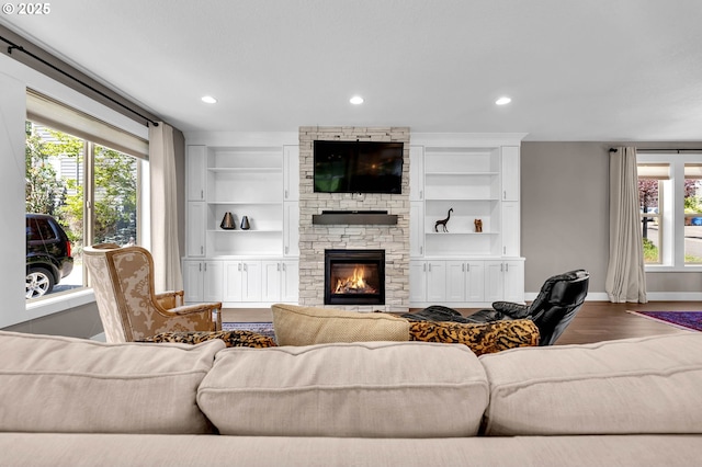 living room with baseboards, healthy amount of natural light, recessed lighting, dark wood-style floors, and a stone fireplace