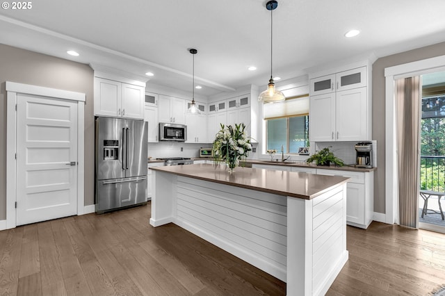 kitchen with appliances with stainless steel finishes, a center island, backsplash, dark wood-type flooring, and recessed lighting