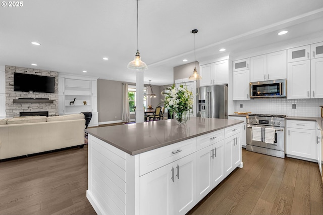 kitchen featuring high quality appliances, a fireplace, dark wood-style floors, recessed lighting, and decorative backsplash